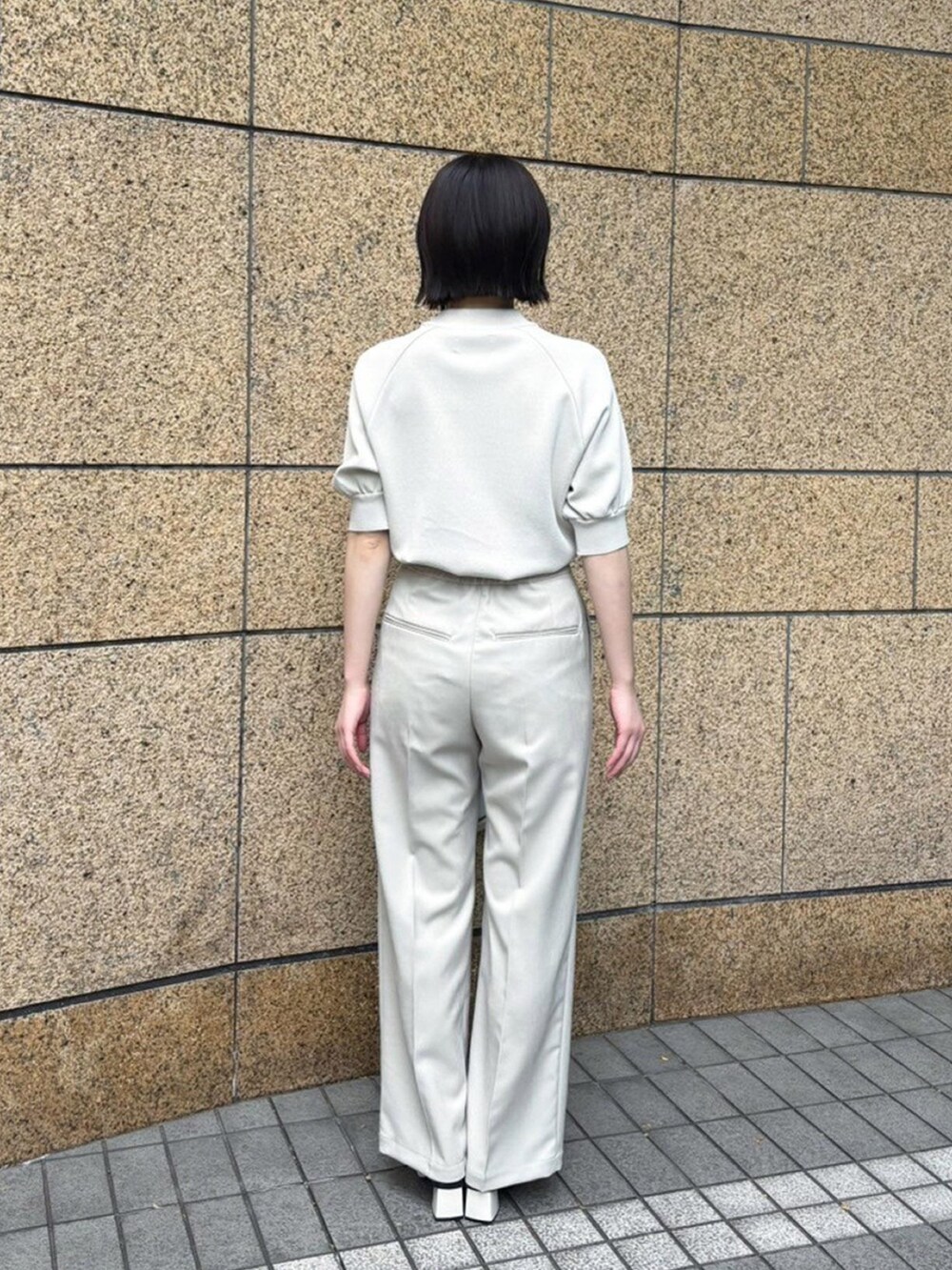 ベージュ系のニット/セーター、ベージュ系のスラックスを着用したレディースの春コーディネートの3枚目の写真