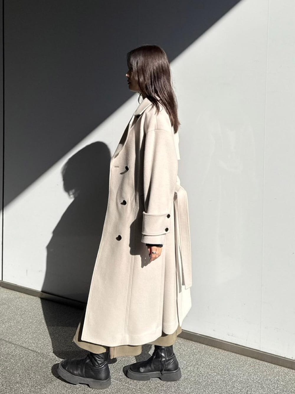 ホワイト系のステンカラーコートを着用したレディースの秋コーディネートの2枚目の写真