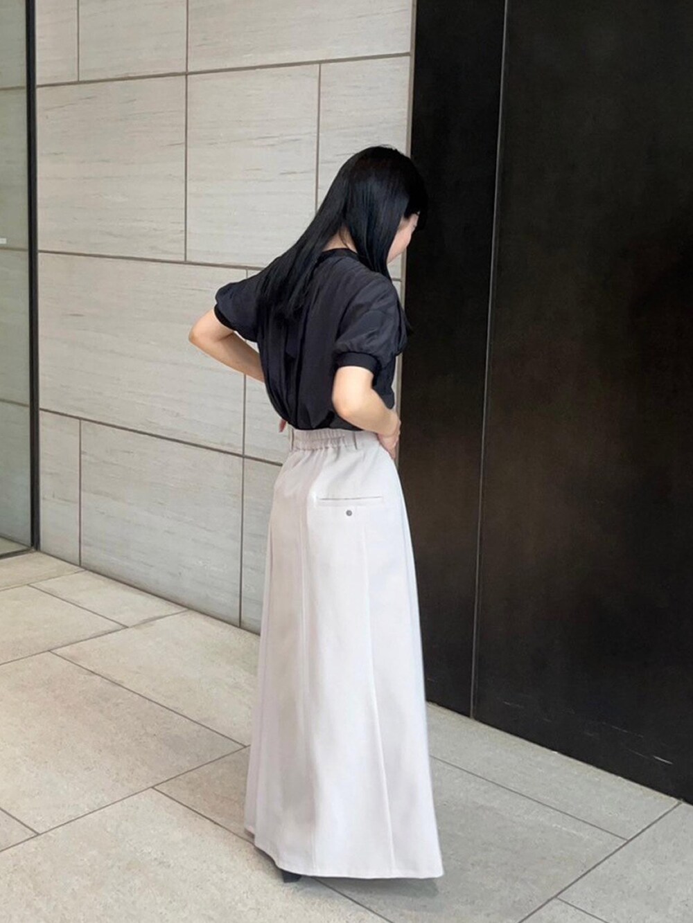 ベージュ系のスカート、ブラック系のシャツ/ブラウスを着用したレディースの春コーディネートの4枚目の写真