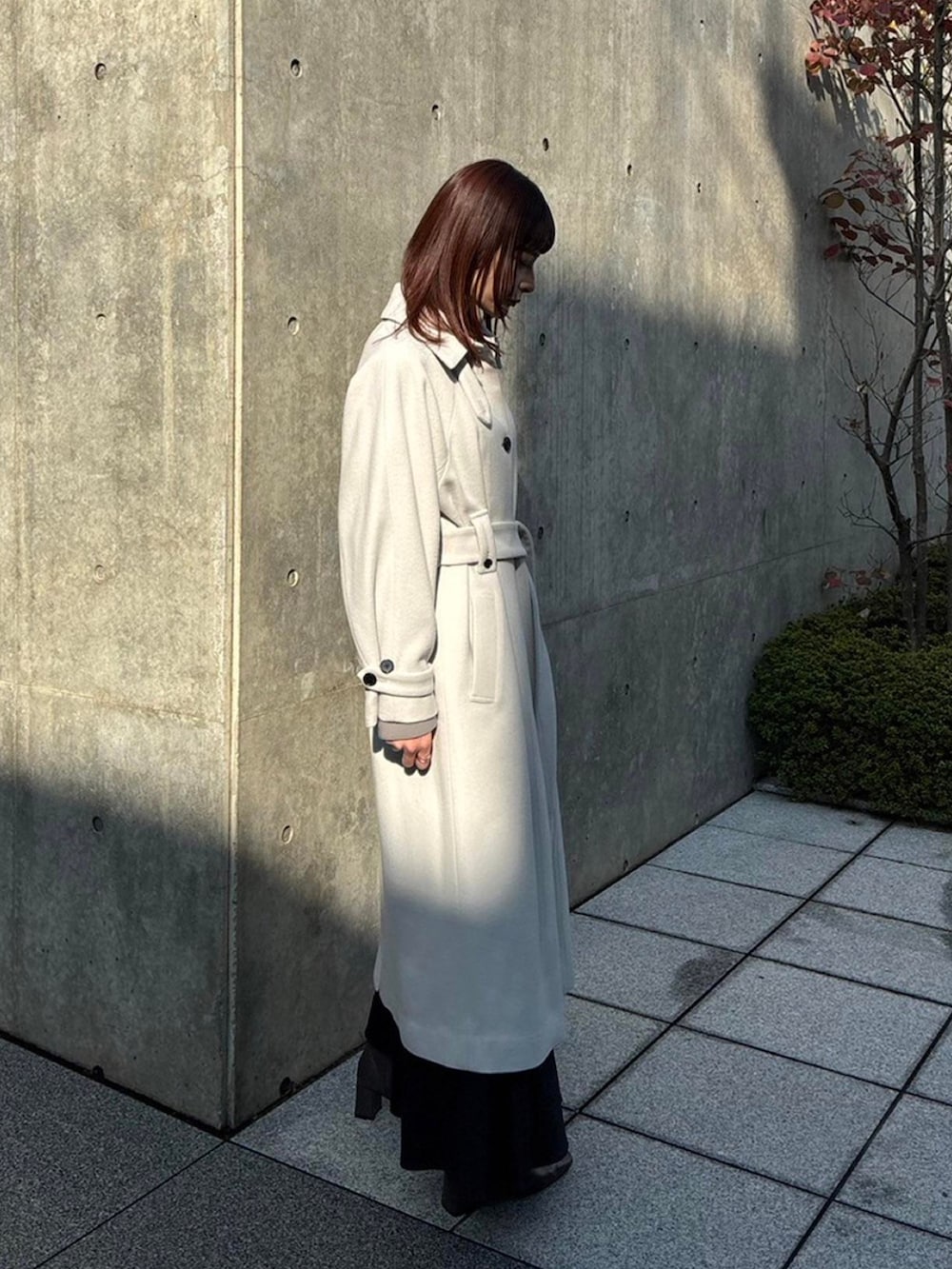 ホワイト系のステンカラーコートを着用したレディースの秋コーディネートの4枚目の写真