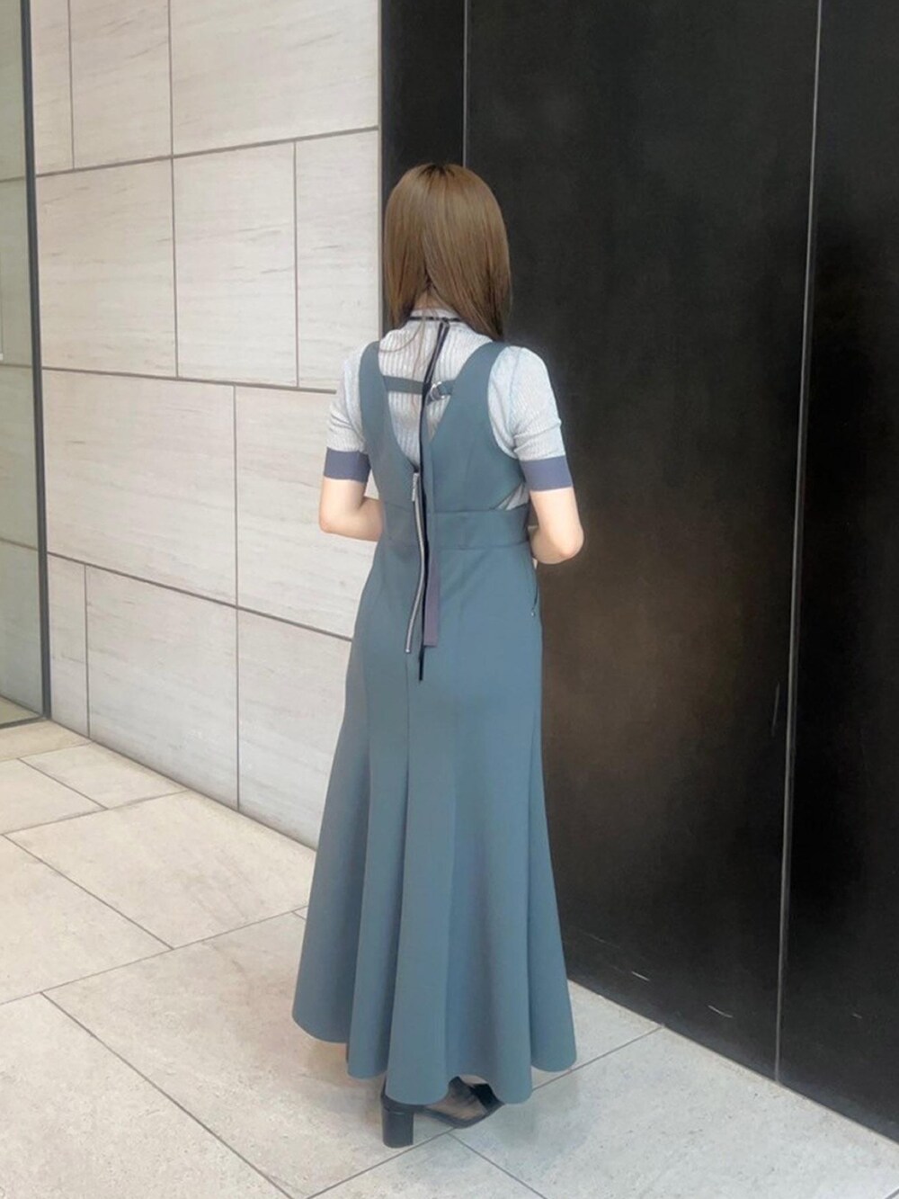 シルバー系のニット/セーター、グレー系のジャンパースカートを着用したレディースの春コーディネートの3枚目の写真