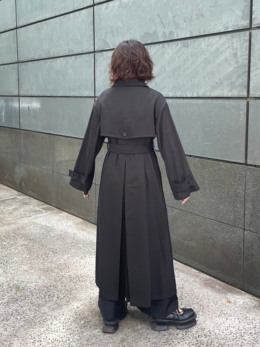 ブラック系のトレンチコートを着用したレディースの秋コーディネートの2枚目の写真