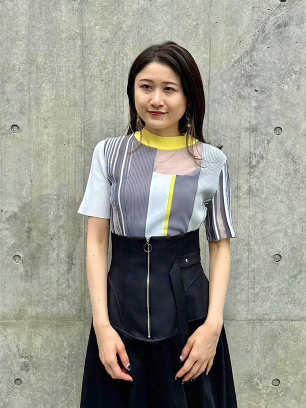 イエロー系のニット/セーター、ブラック系のスカートを着用したレディースの春コーディネートの5枚目の写真