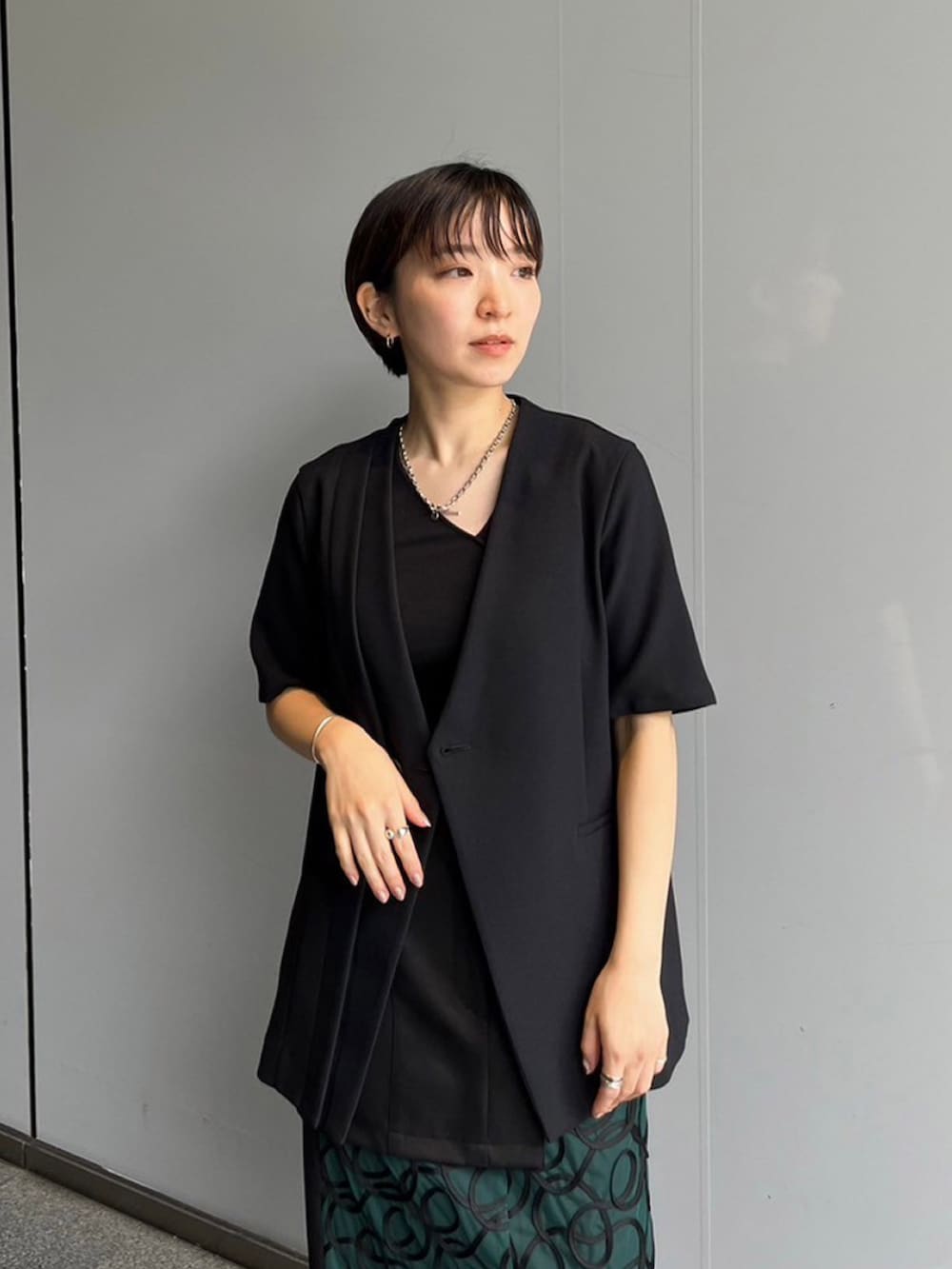 ブラック系のノーカラージャケット、グリーン系のスカートを着用したレディースの夏コーディネートの4枚目の写真