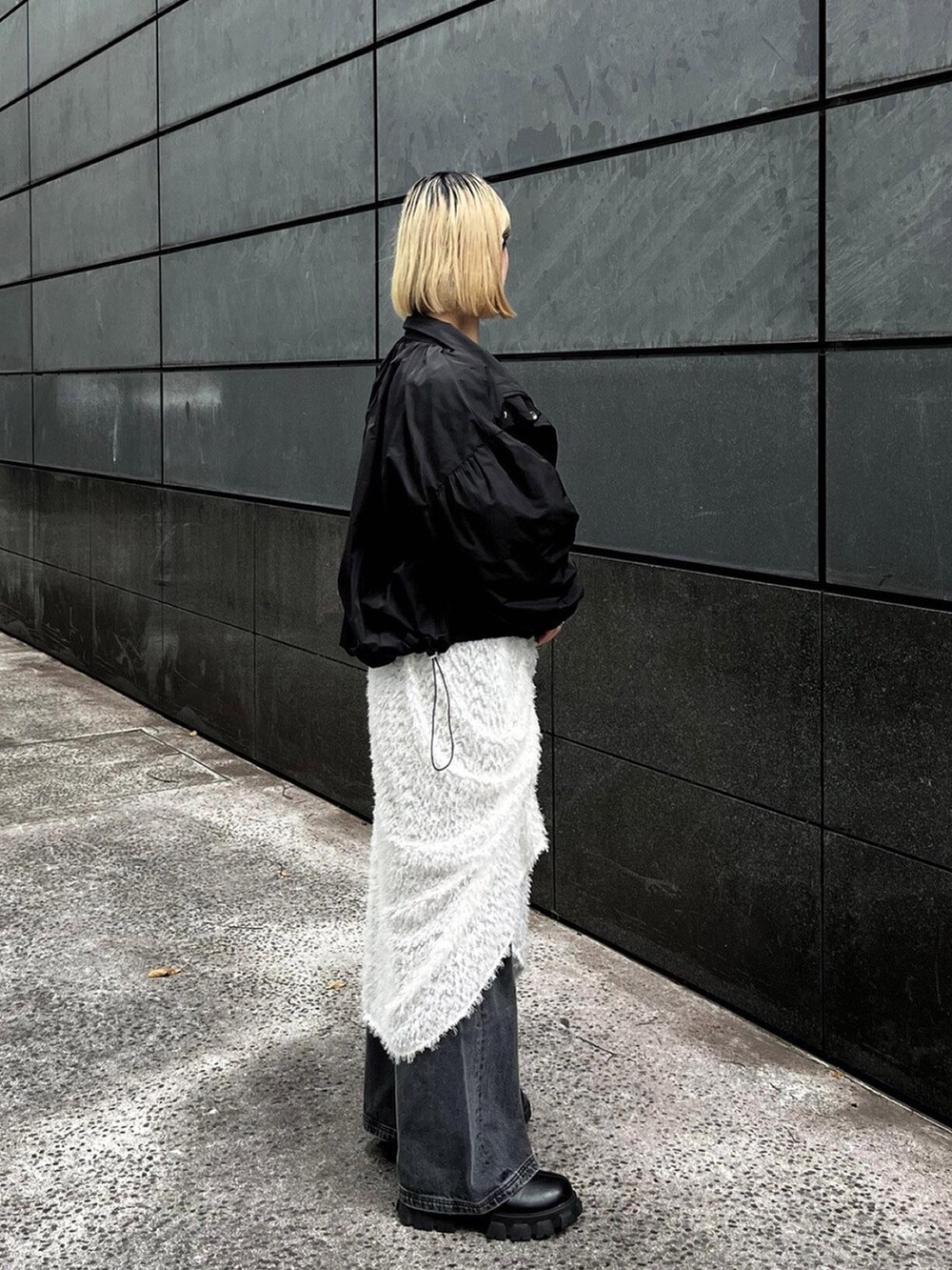 ブラック系のブルゾン、ホワイト系のスカートを着用したレディースの秋コーディネートの2枚目の写真