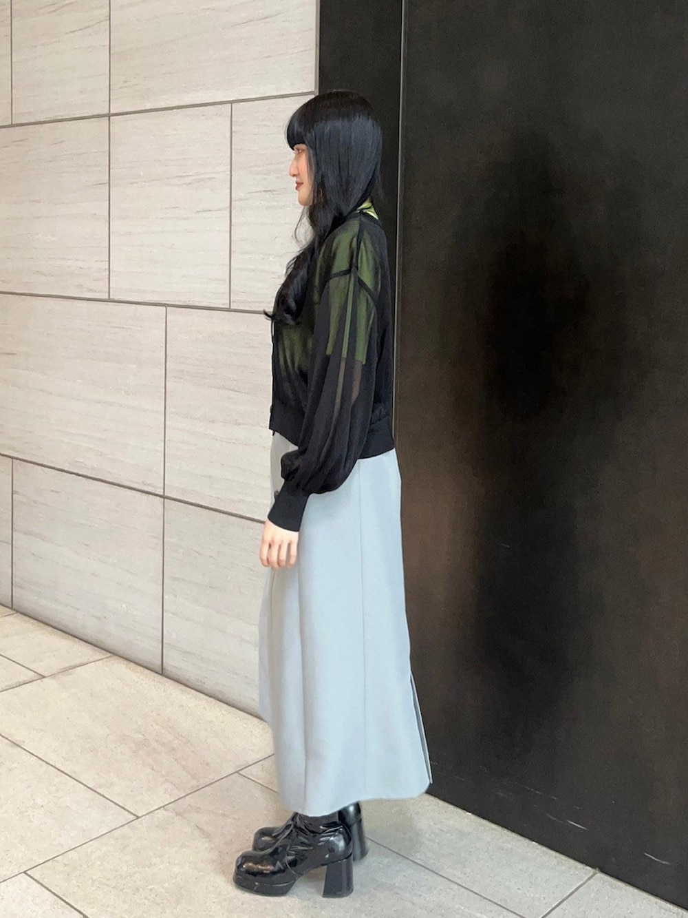 グレー系のスカート、ブラック系のカーディガン/ボレロ、グリーン系のニット/セーターを着用したレディースの春コーディネートの2枚目の写真