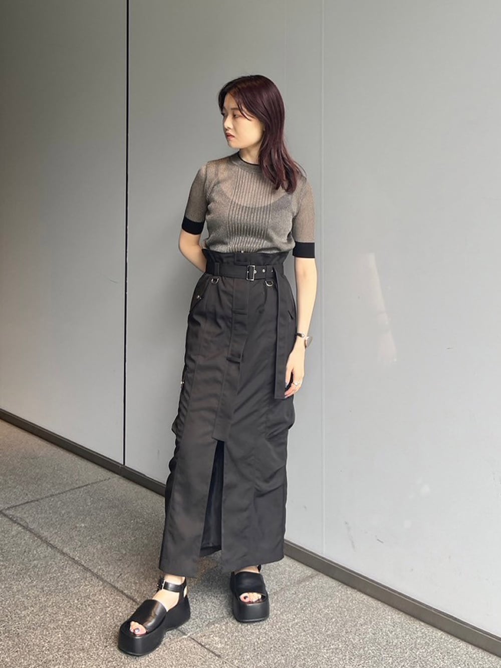 ゴールド系のニット/セーター、ブラック系のスカートを着用したレディースの夏コーディネートの2枚目の写真