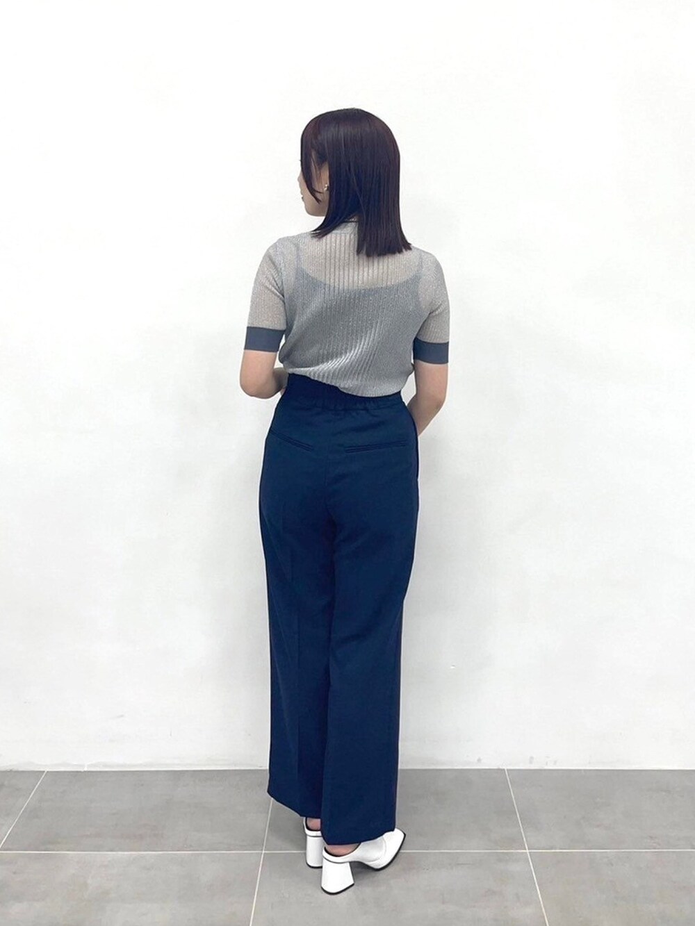 シルバー系のニット/セーター、ブルー系のスラックスを着用したレディースの春コーディネートの3枚目の写真