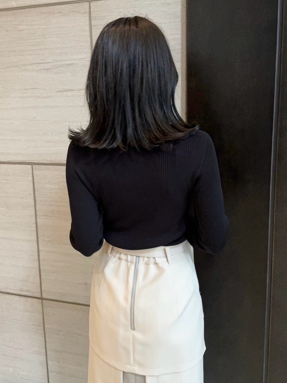 ベージュ系のスカート、ブラック系のニット/セーターを着用したレディースの春コーディネートの8枚目の写真