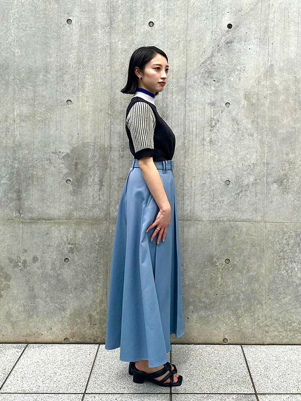 ブラック系のニット/セーター、ブルー系のスカートを着用したレディースの春コーディネートの4枚目の写真