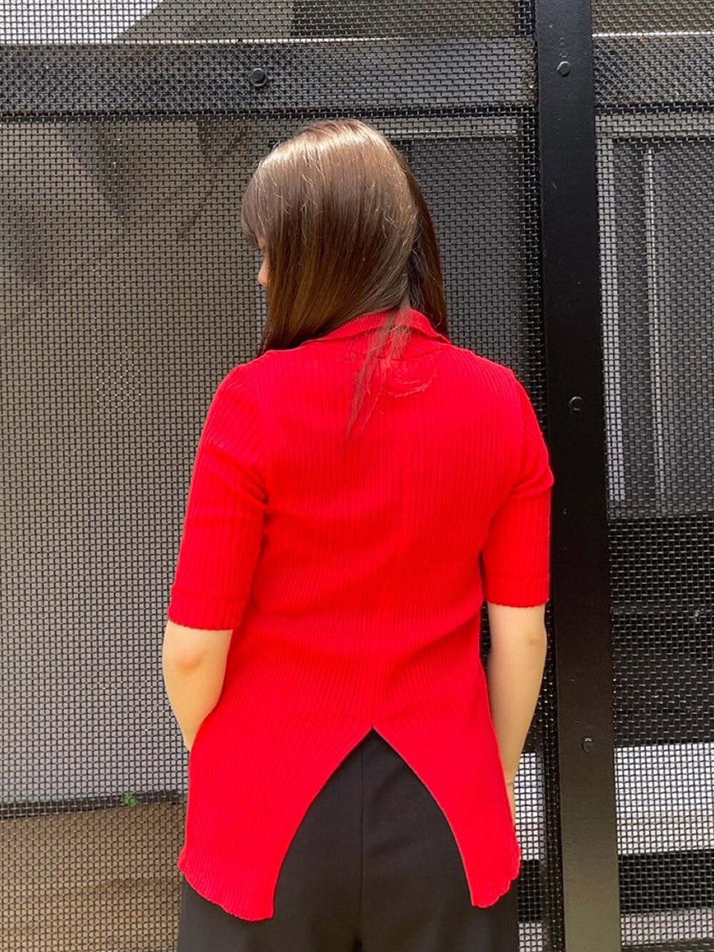 ブラック系のスラックス、レッド系のニット/セーターを着用したレディースの春コーディネートの5枚目の写真