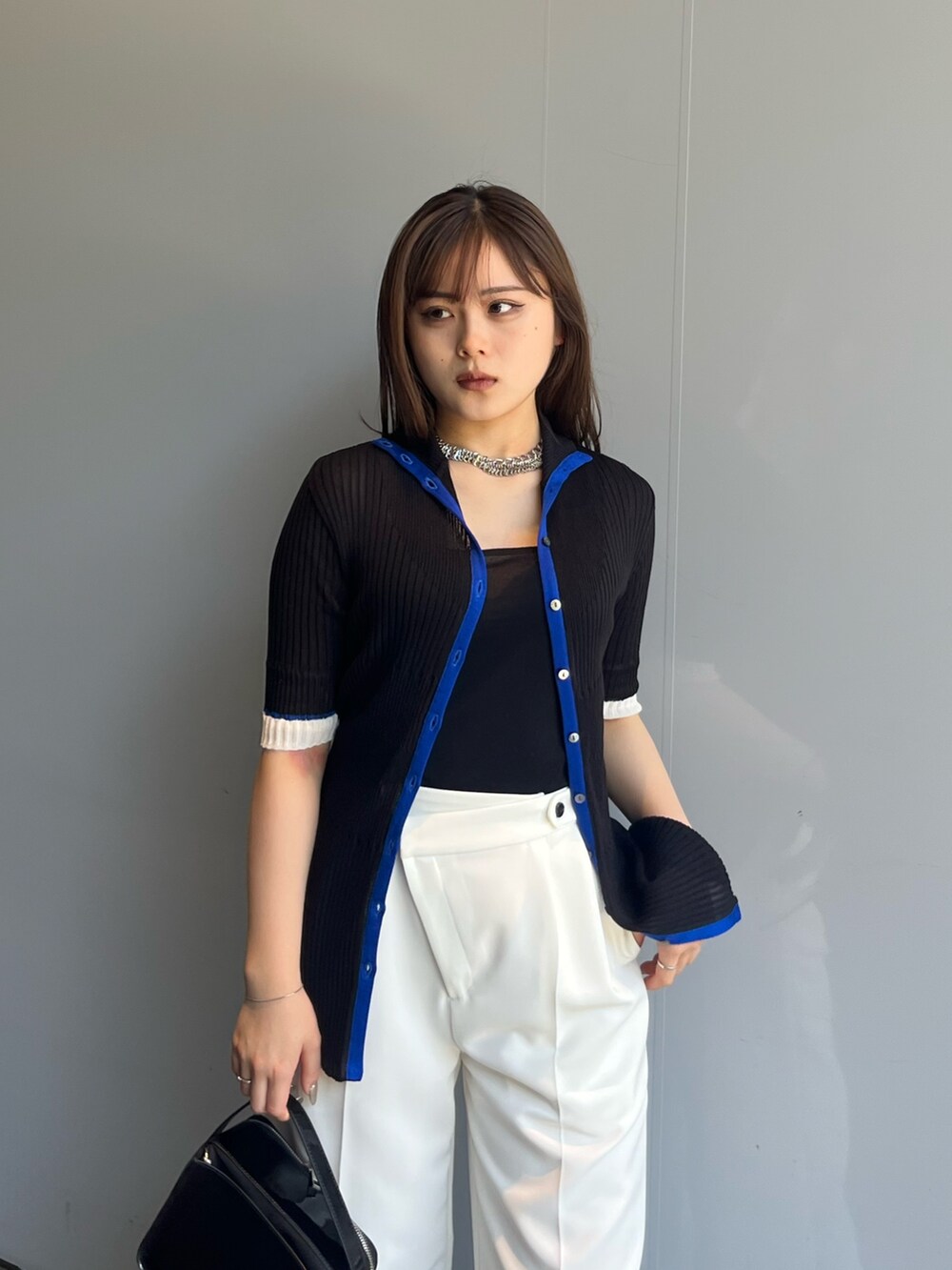 ブラック系のニット/セーター、ホワイト系のスラックスを着用したレディースの夏コーディネートの3枚目の写真