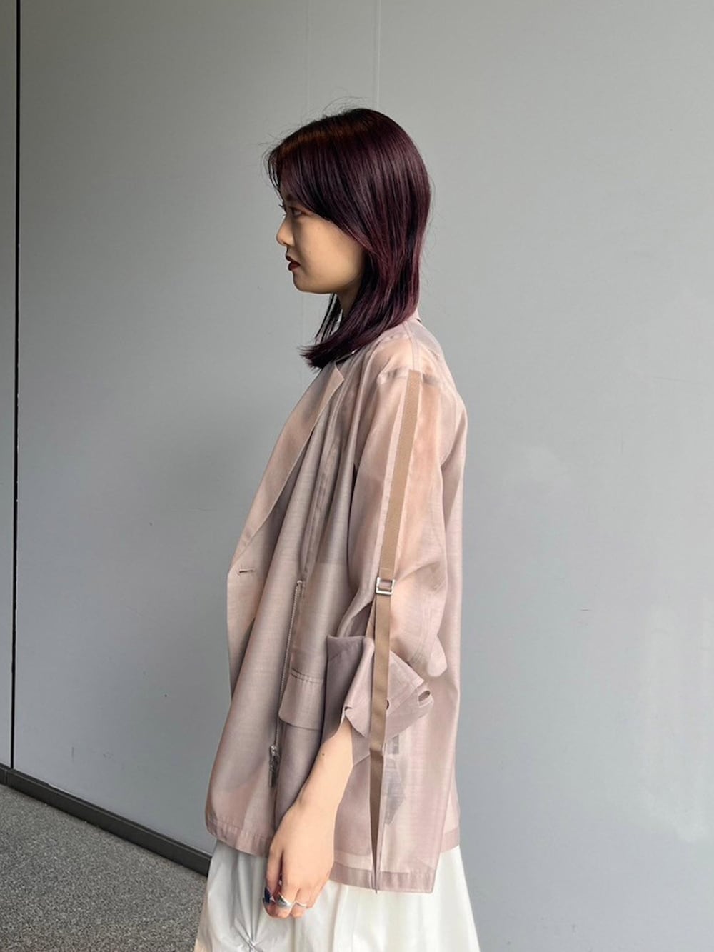 ベージュ系のテーラードジャケット、ホワイト系のスカート、ブラック系のサンダルを着用したレディースの夏コーディネートの3枚目の写真