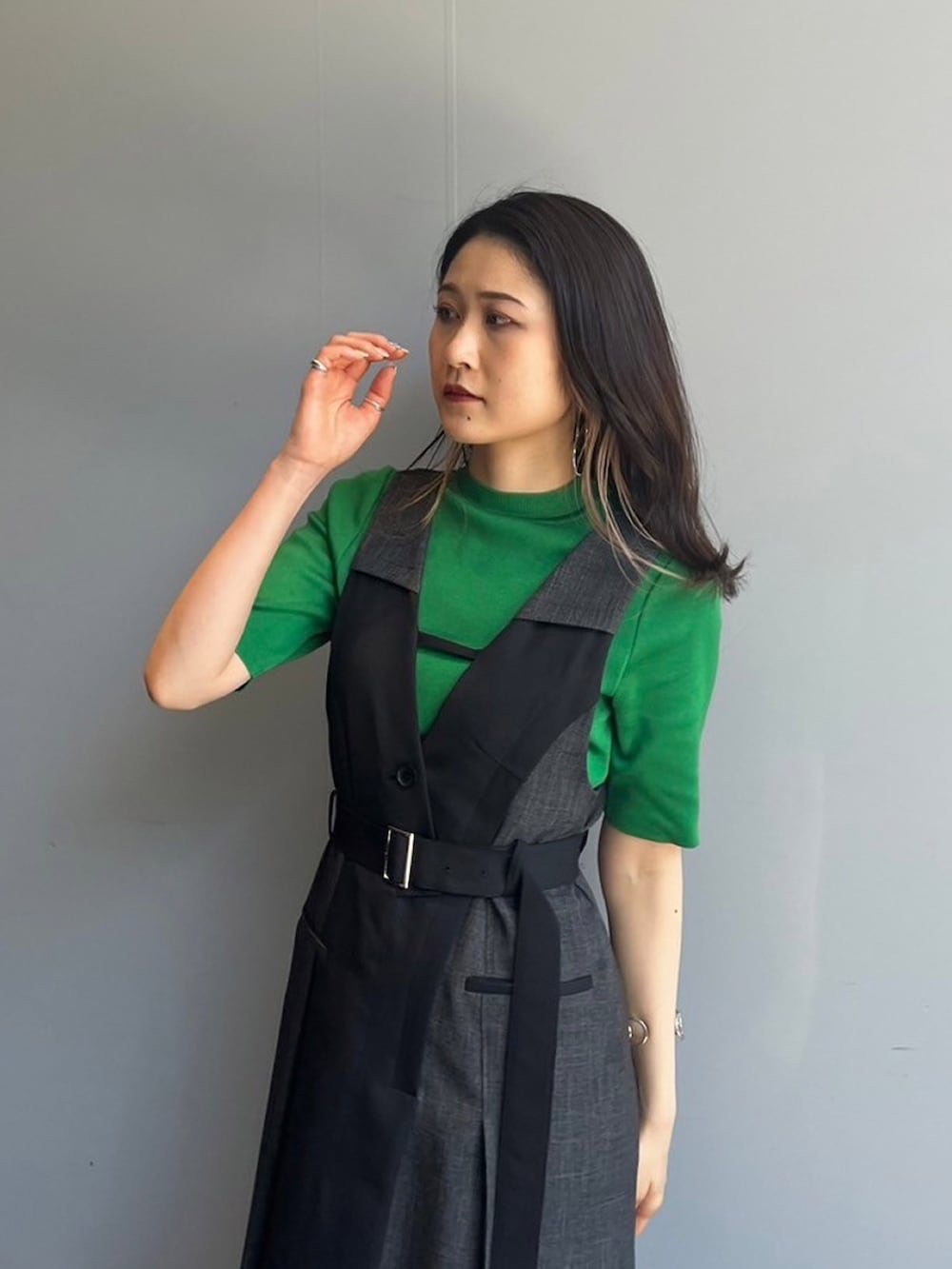 グリーン系のニット/セーター、ブラック系のジャンパースカートを着用したレディースの夏コーディネートの3枚目の写真