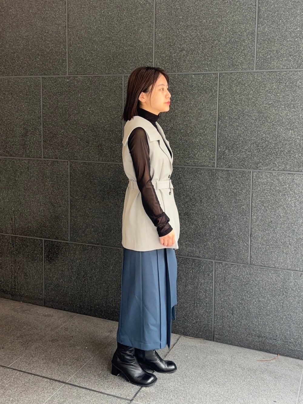 グレー系のテーラードジャケット、ブルー系のスカートを着用したレディースの秋コーディネートの2枚目の写真