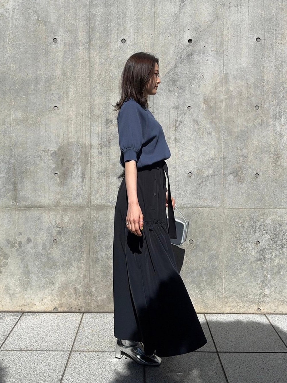 グレー系のニット/セーター、ブラック系のスカートを着用したレディースの春コーディネートの2枚目の写真