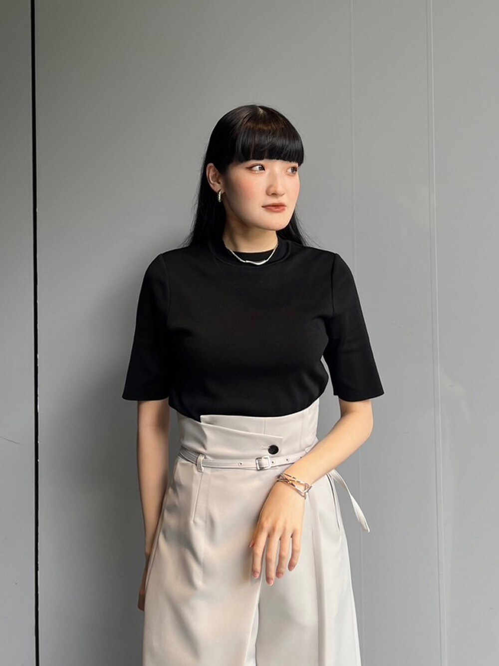 ブラック系のニット/セーター、グレー系のスラックスを着用したレディースの夏コーディネートの4枚目の写真