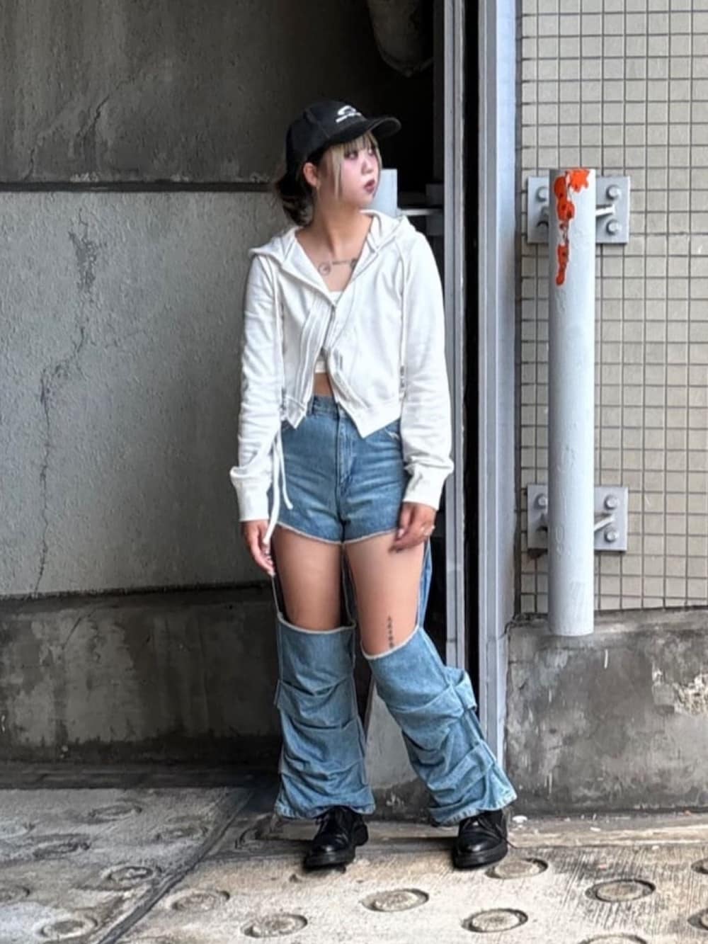 ブルー系のデニムパンツ、ホワイト系のパーカー、ブラック系のキャップを着用したレディースの秋コーディネートの2枚目の写真