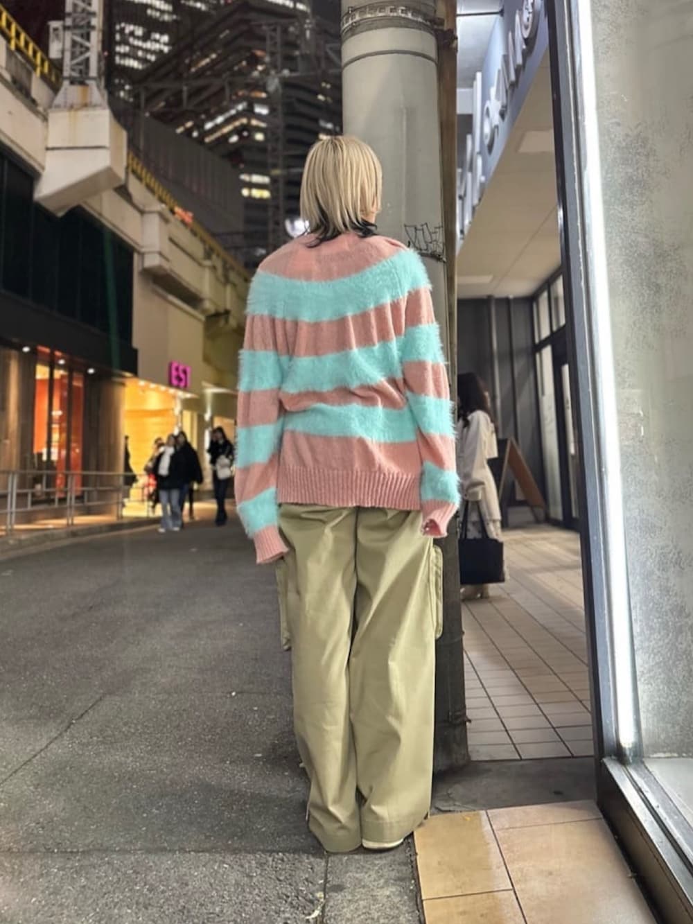 ピンク系のニット/セーター、ベージュ系のパンツ、ブラック系のスニーカーを着用したレディースの冬コーディネートの4枚目の写真