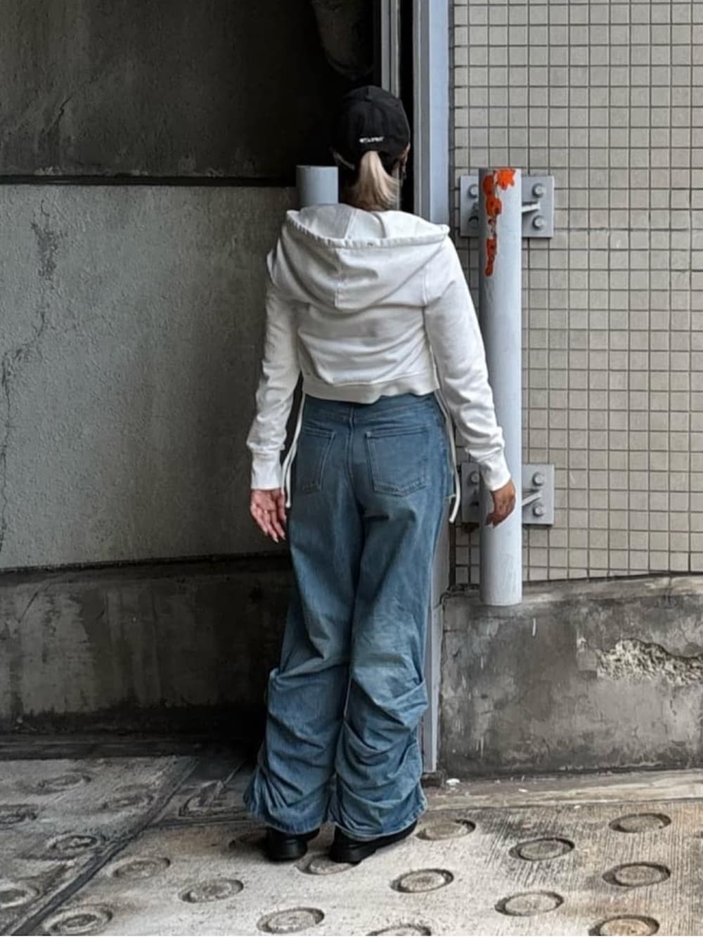 ブルー系のデニムパンツ、ホワイト系のパーカー、ブラック系のキャップを着用したレディースの秋コーディネートの4枚目の写真