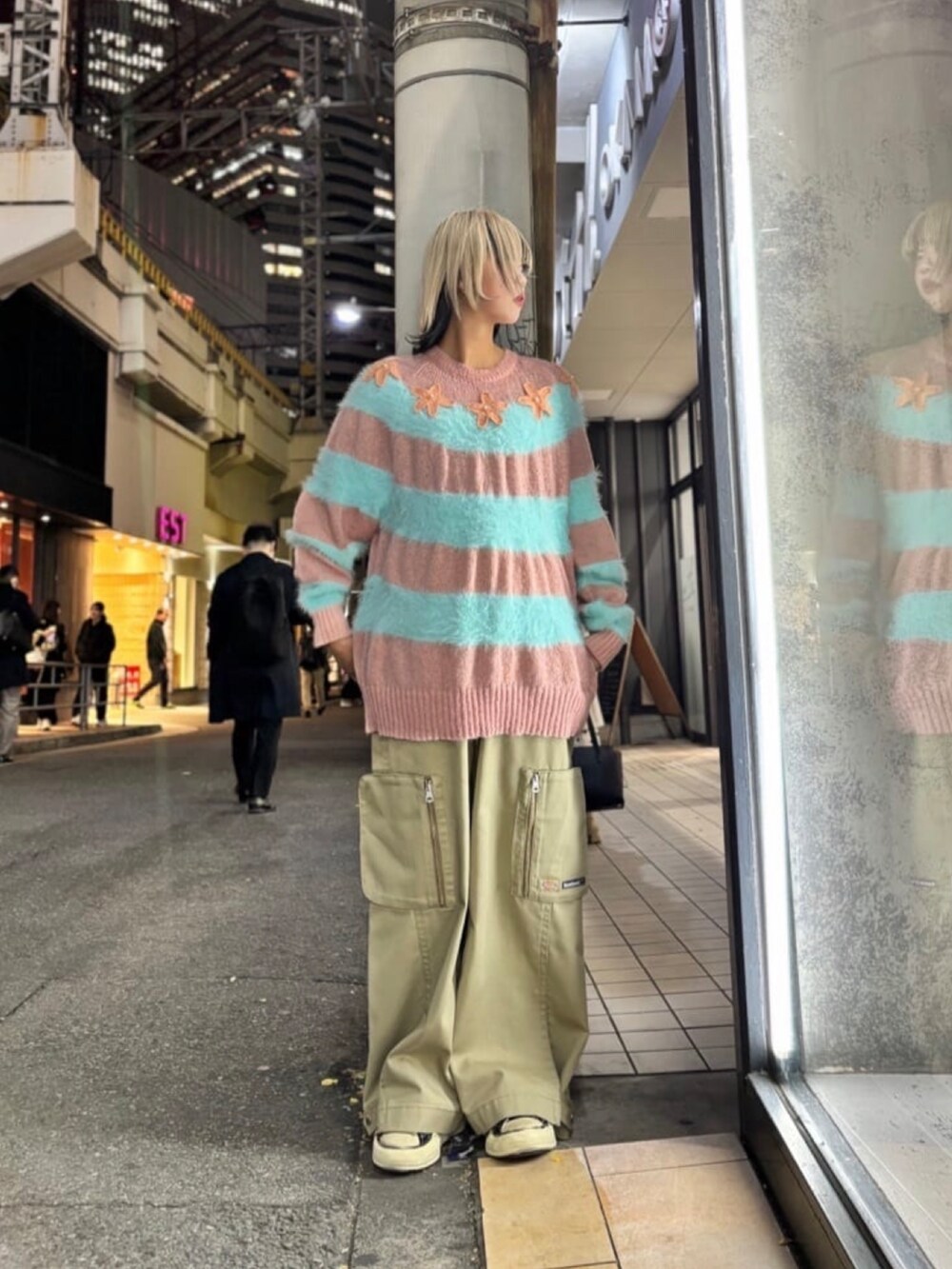 ピンク系のニット/セーター、ベージュ系のパンツ、ブラック系のスニーカーを着用したレディースの冬コーディネートの2枚目の写真