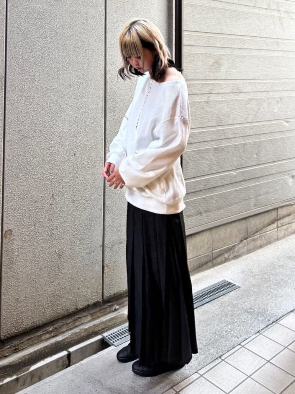 ブラック系のスカート、ホワイト系のトップスを着用したレディースの秋コーディネートの2枚目の写真