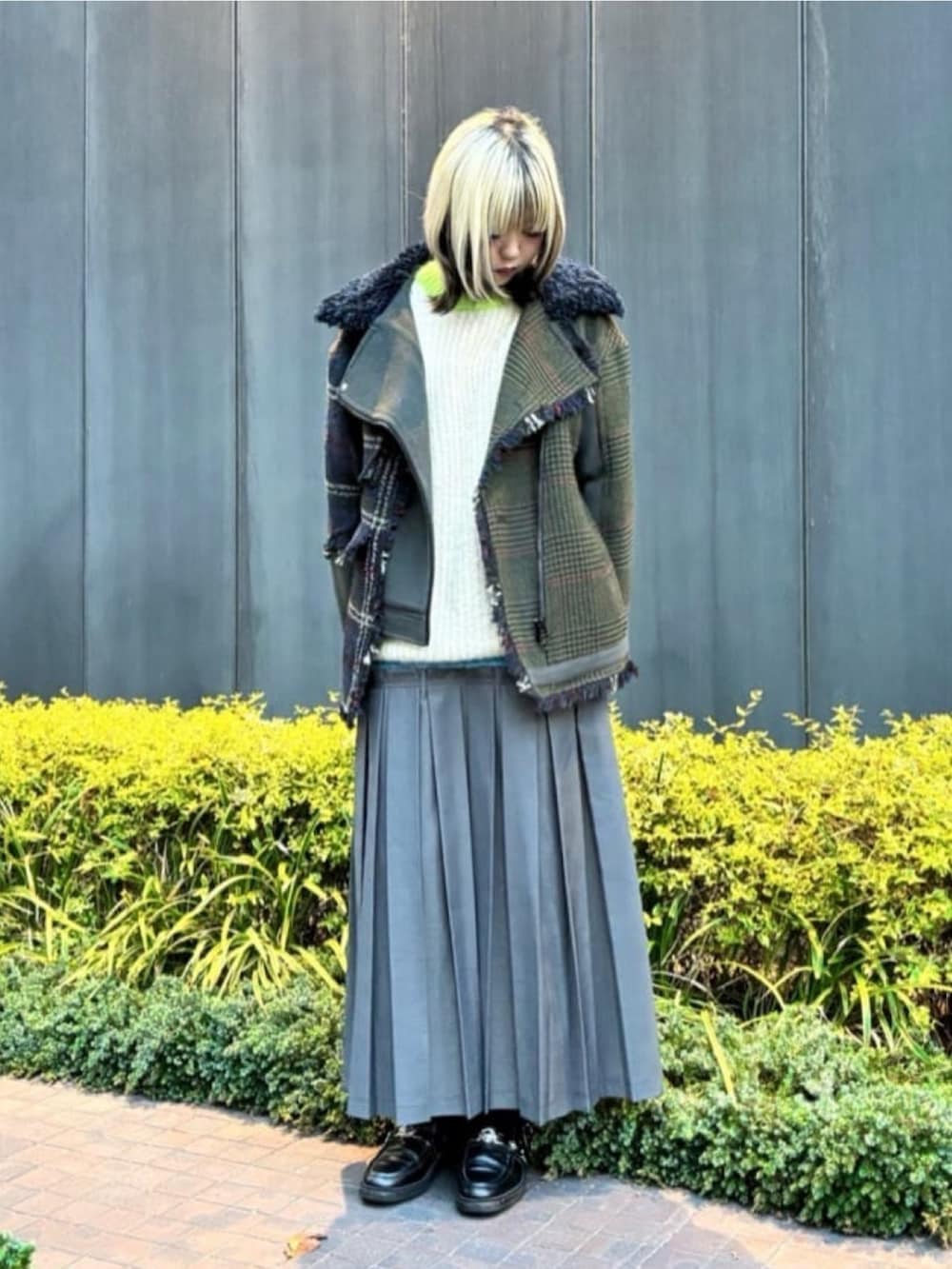 イエロー系のニット/セーター、グリーン系のブルゾン、グレー系のスカートを着用したレディースの冬コーディネートの2枚目の写真