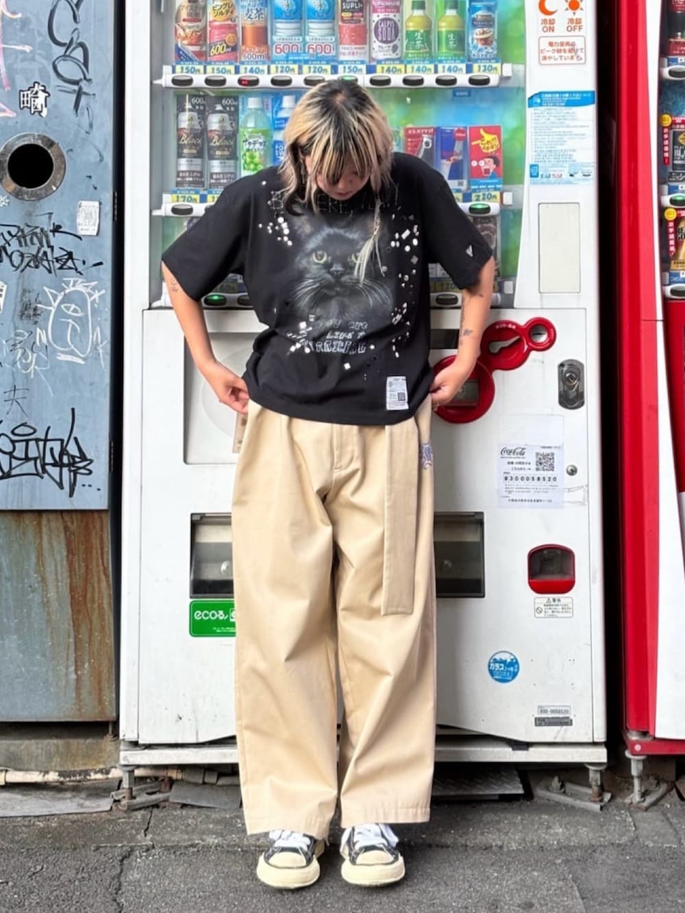 ブラック系のスニーカー、ベージュ系のチノパンツ、ブラック系のTシャツ/カットソーを着用したレディースの秋コーディネートの2枚目の写真