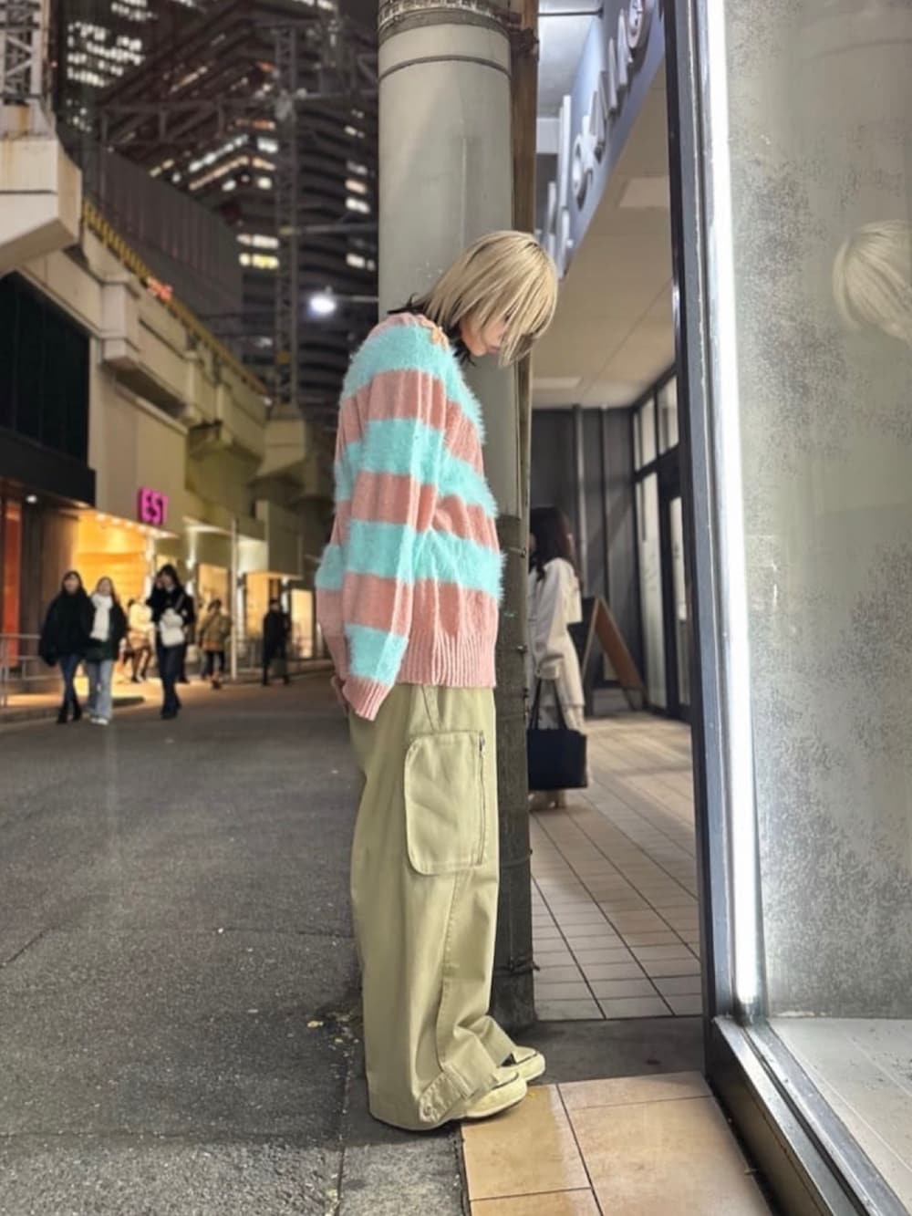 ピンク系のニット/セーター、ベージュ系のパンツ、ブラック系のスニーカーを着用したレディースの冬コーディネートの3枚目の写真