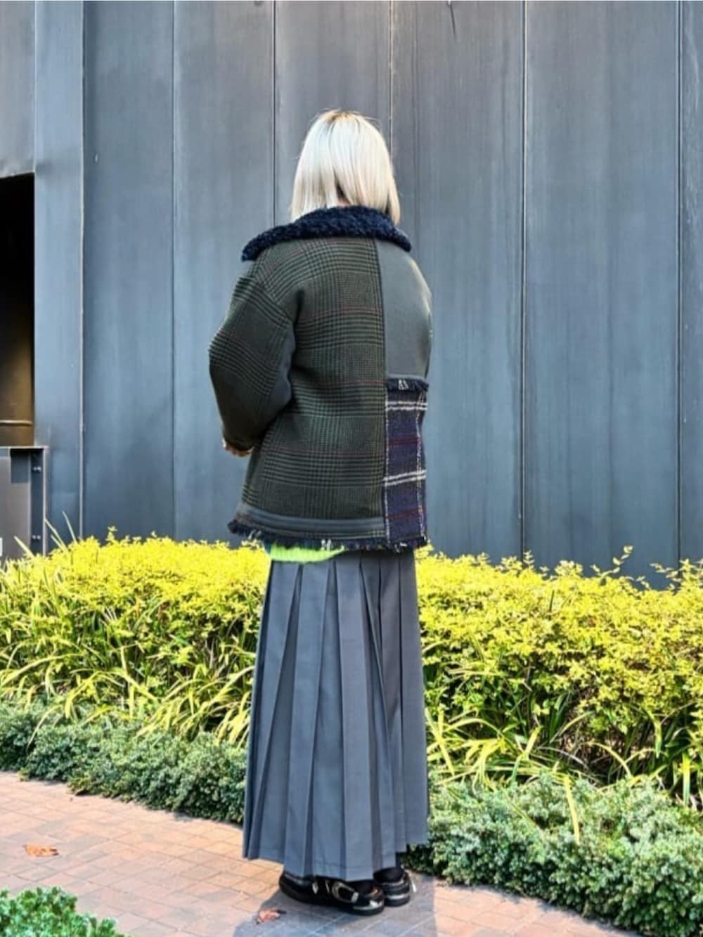 イエロー系のニット/セーター、グリーン系のブルゾン、グレー系のスカートを着用したレディースの冬コーディネートの4枚目の写真