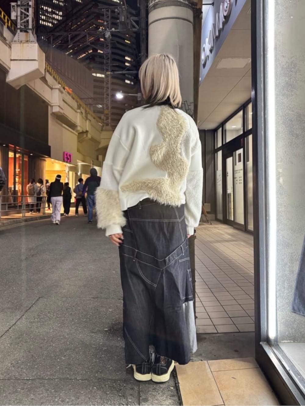 ブラック系のスカート、ホワイト系のブルゾン、ブラック系のスニーカーを着用したレディースの冬コーディネートの3枚目の写真