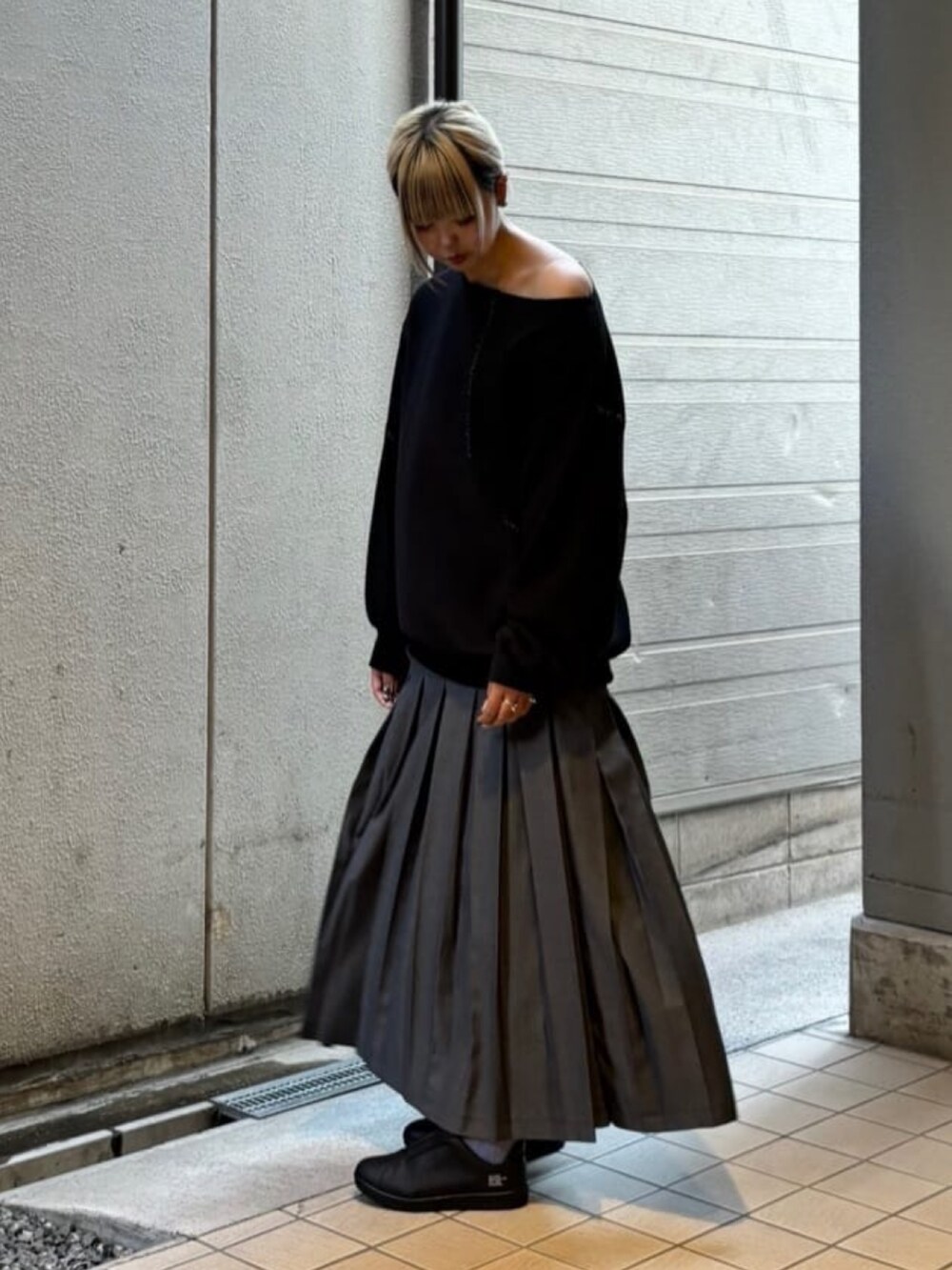 グレー系のスカート、ブラック系のトップスを着用したレディースの秋コーディネートの3枚目の写真