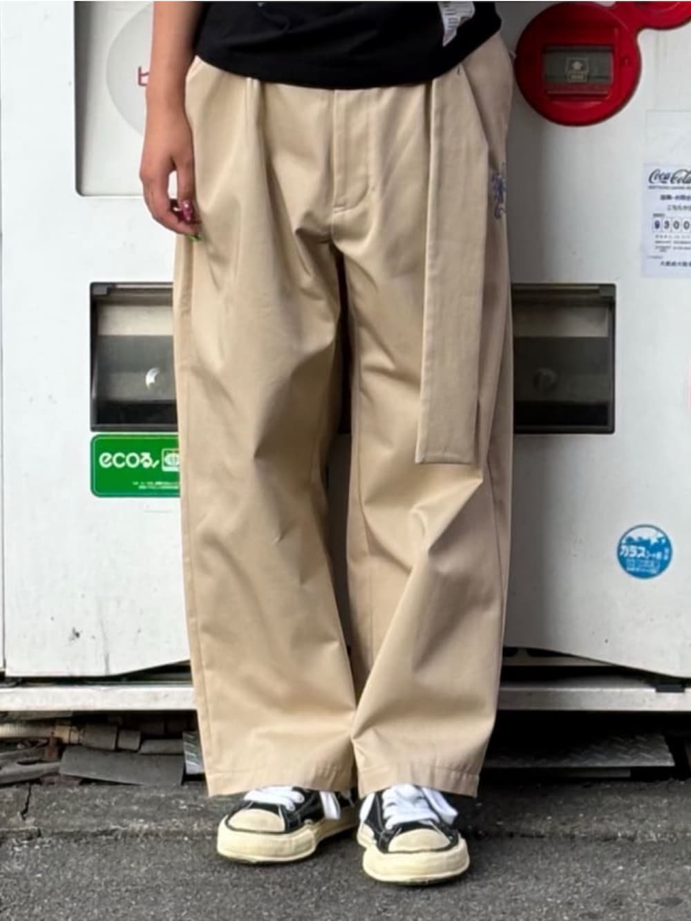 ブラック系のスニーカー、ベージュ系のチノパンツ、ブラック系のTシャツ/カットソーを着用したレディースの秋コーディネートの4枚目の写真