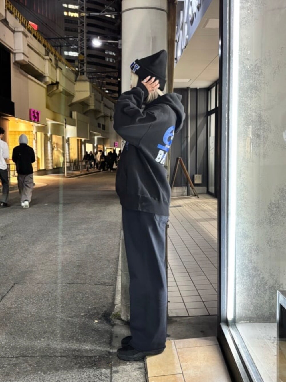 ブラック系のトップス、ブルー系のパンツ、ブラック系の帽子を着用したレディースの冬コーディネートの2枚目の写真