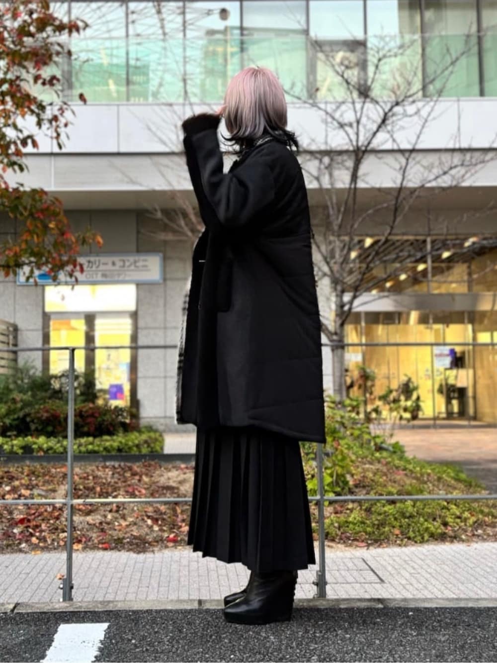 ブラック系のチェスターコート、ブラック系のスカートを着用したレディースの冬コーディネートの2枚目の写真