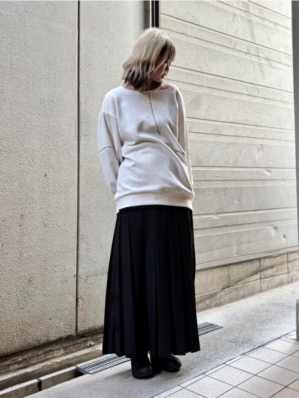 ブラック系のスカート、ホワイト系のトップスを着用したレディースの秋コーディネートの3枚目の写真