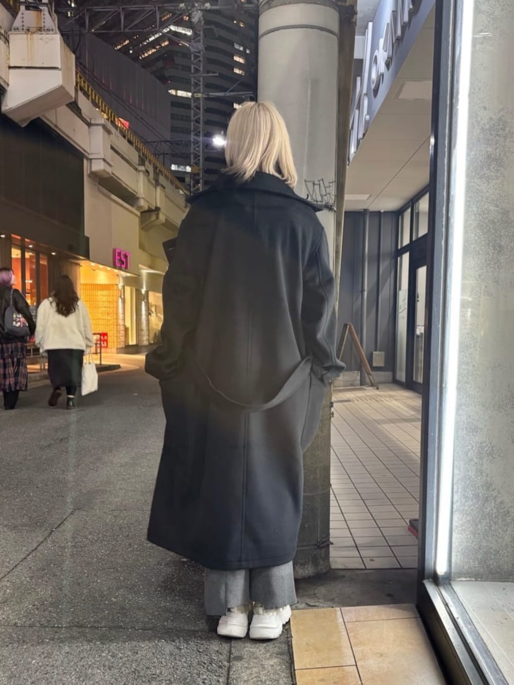 ブラック系のトレンチコート、グレー系のその他パンツ、ブラック系のニット/セーターを着用したレディースの冬コーディネートの3枚目の写真