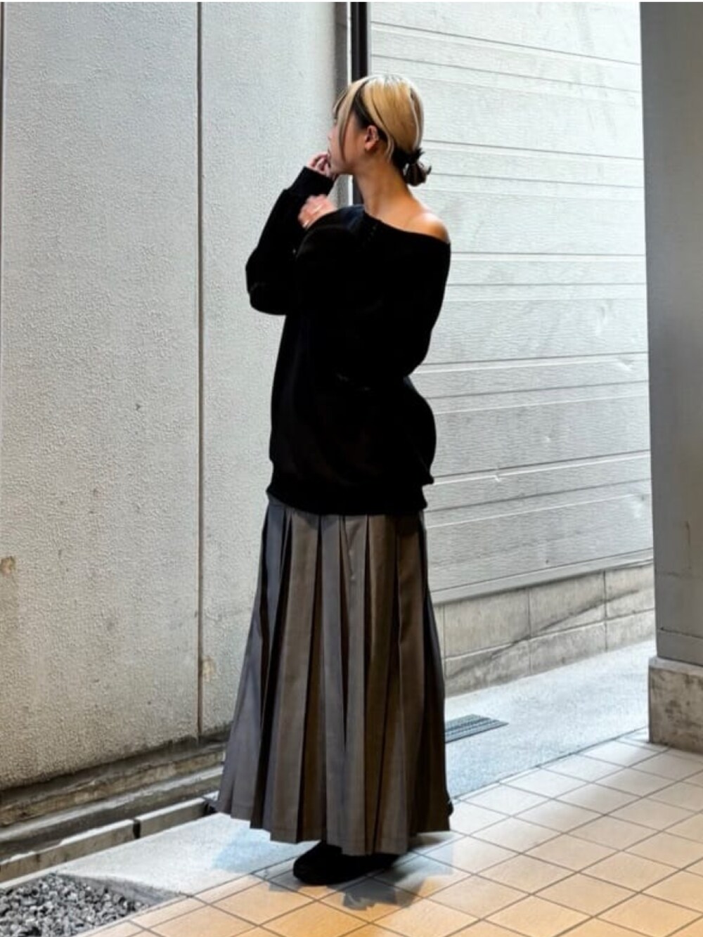 グレー系のスカート、ブラック系のトップスを着用したレディースの秋コーディネートの2枚目の写真