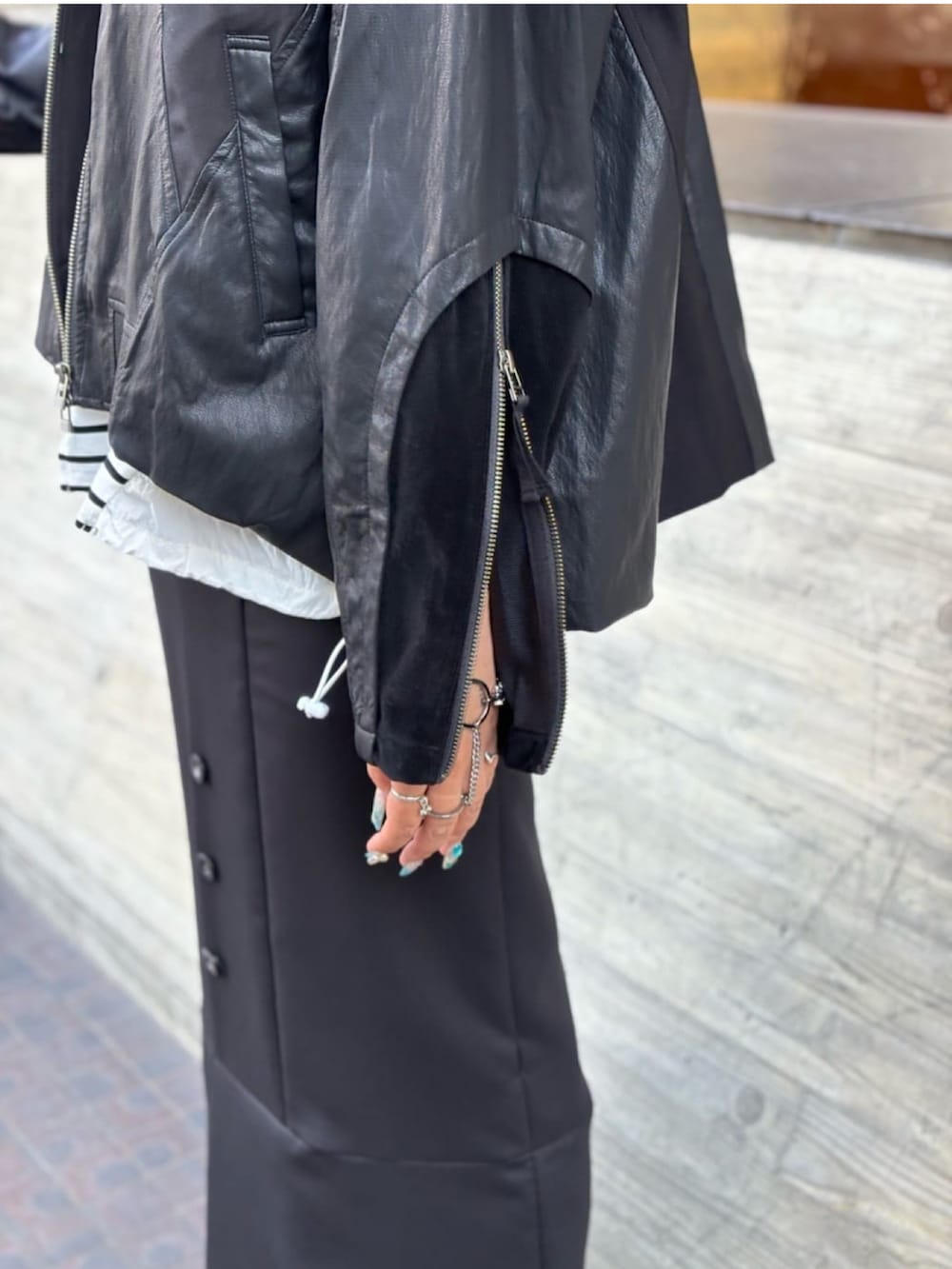 ブラック系のブルゾン、ホワイト系のTシャツ/カットソー、ブラック系のスカートを着用したレディースの秋コーディネートの4枚目の写真