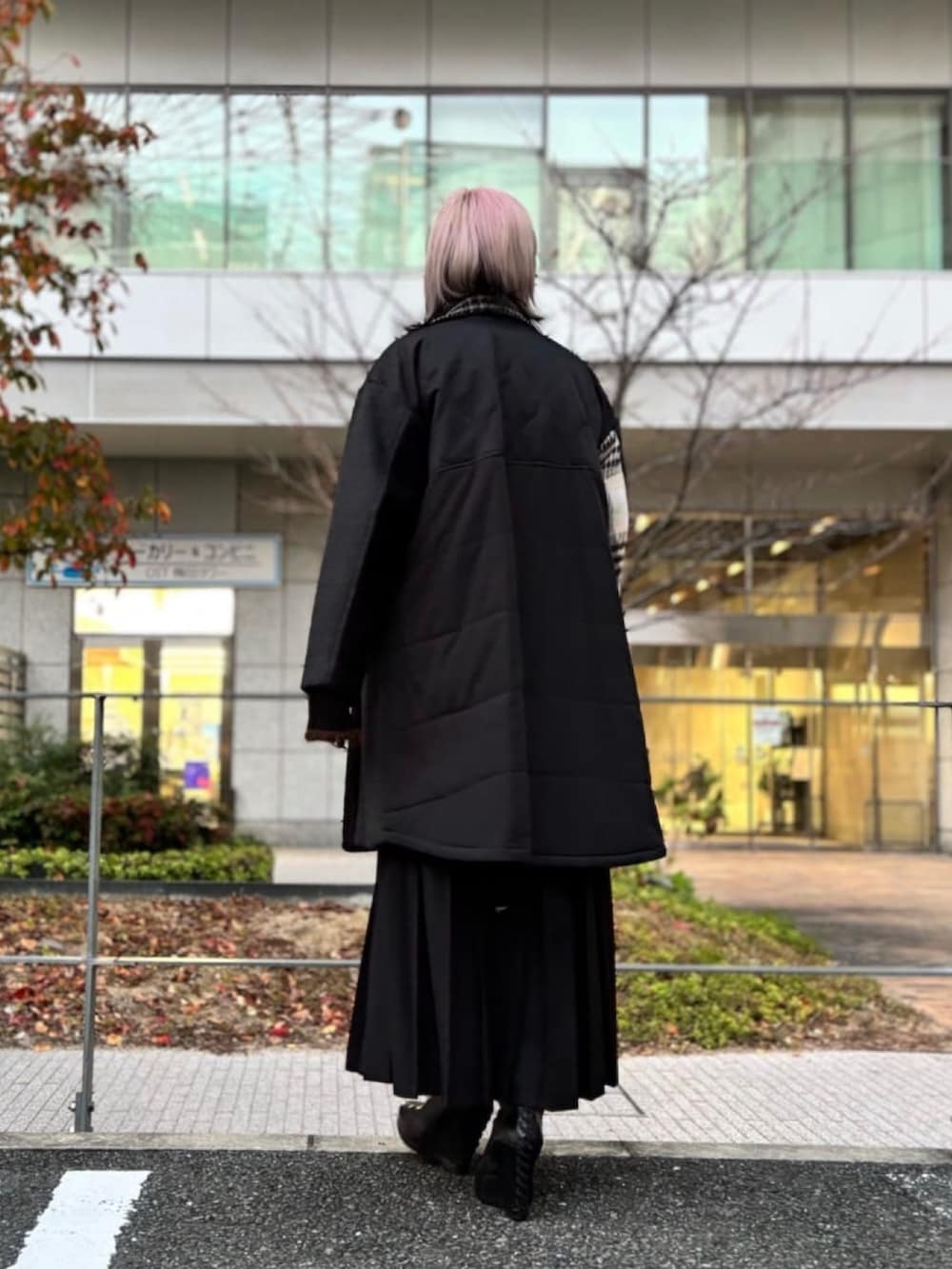 ブラック系のチェスターコート、ブラック系のスカートを着用したレディースの冬コーディネートの3枚目の写真