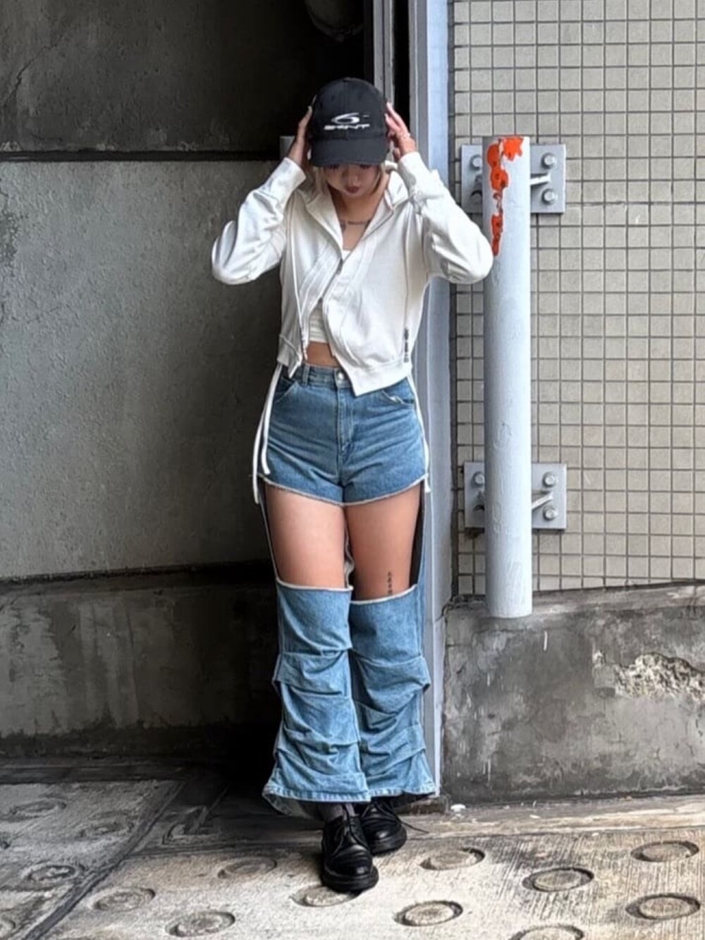 ブルー系のデニムパンツ、ホワイト系のパーカー、ブラック系のキャップを着用したレディースの秋コーディネートの3枚目の写真