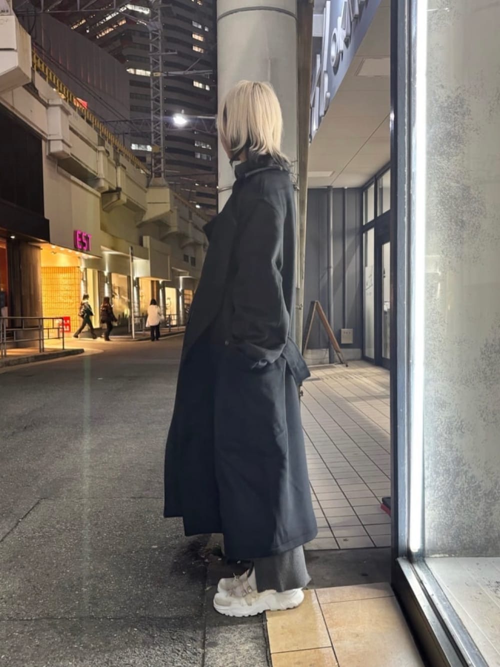 ブラック系のトレンチコート、グレー系のその他パンツ、ブラック系のニット/セーターを着用したレディースの冬コーディネートの2枚目の写真