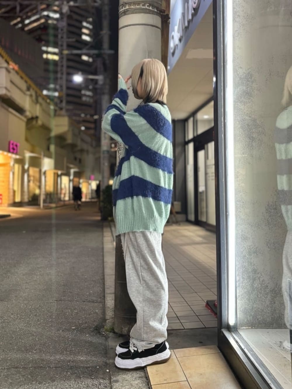 ブルー系のニット/セーター、グレー系のパンツ、ブラック系のスニーカーを着用したレディースの冬コーディネートの2枚目の写真