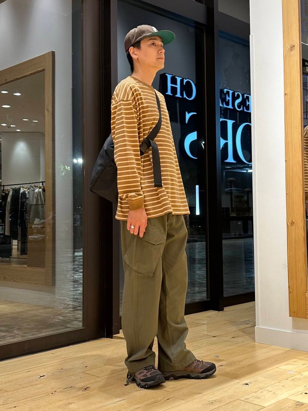 ブラック系のショルダーバッグ、ブラウン系のスニーカー、ベージュ系のTシャツ/カットソーを着用したメンズの夏コーディネートの2枚目の写真