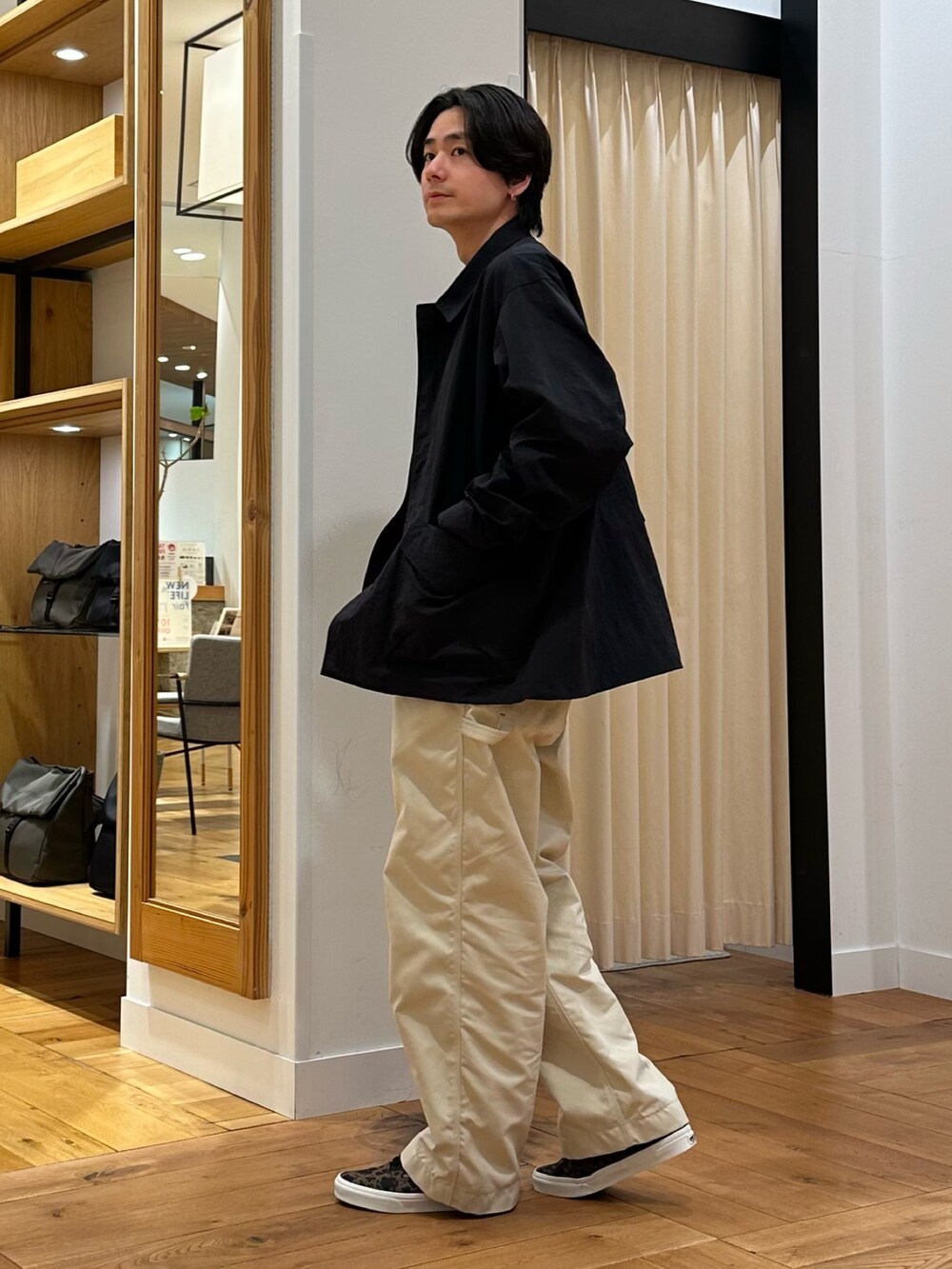 ブラック系のナイロンジャケット、グレー系のニット/セーター、ホワイト系のその他パンツを着用したメンズの春コーディネートの4枚目の写真