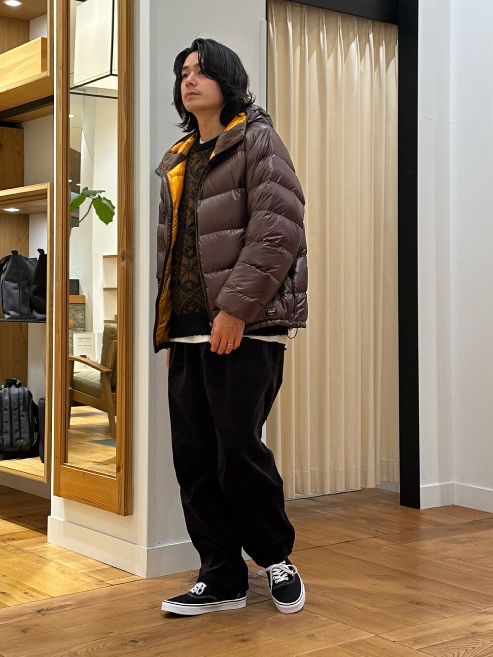 ブラウン系のダウンジャケット/コート、ブラウン系のニット/セーター、グレー系のその他パンツを着用したメンズの冬コーディネートの2枚目の写真