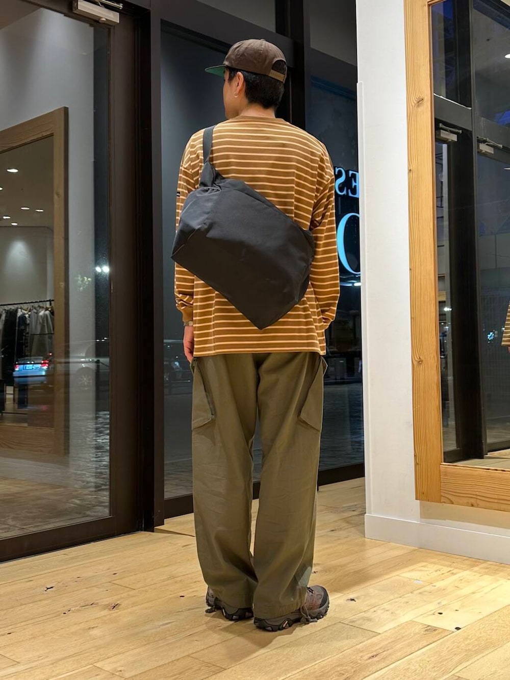 ブラック系のショルダーバッグ、ブラウン系のスニーカー、ベージュ系のTシャツ/カットソーを着用したメンズの夏コーディネートの3枚目の写真