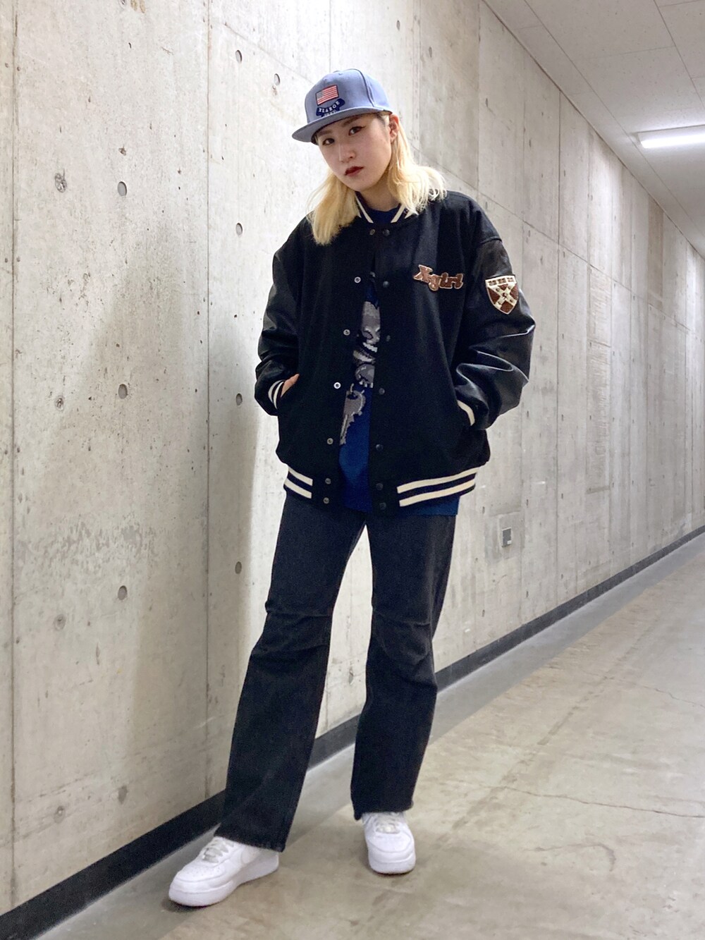 ブラック系のスタジャン、ブラック系のデニムパンツ、ブルー系のキャップを着用したレディースの秋コーディネートの2枚目の写真