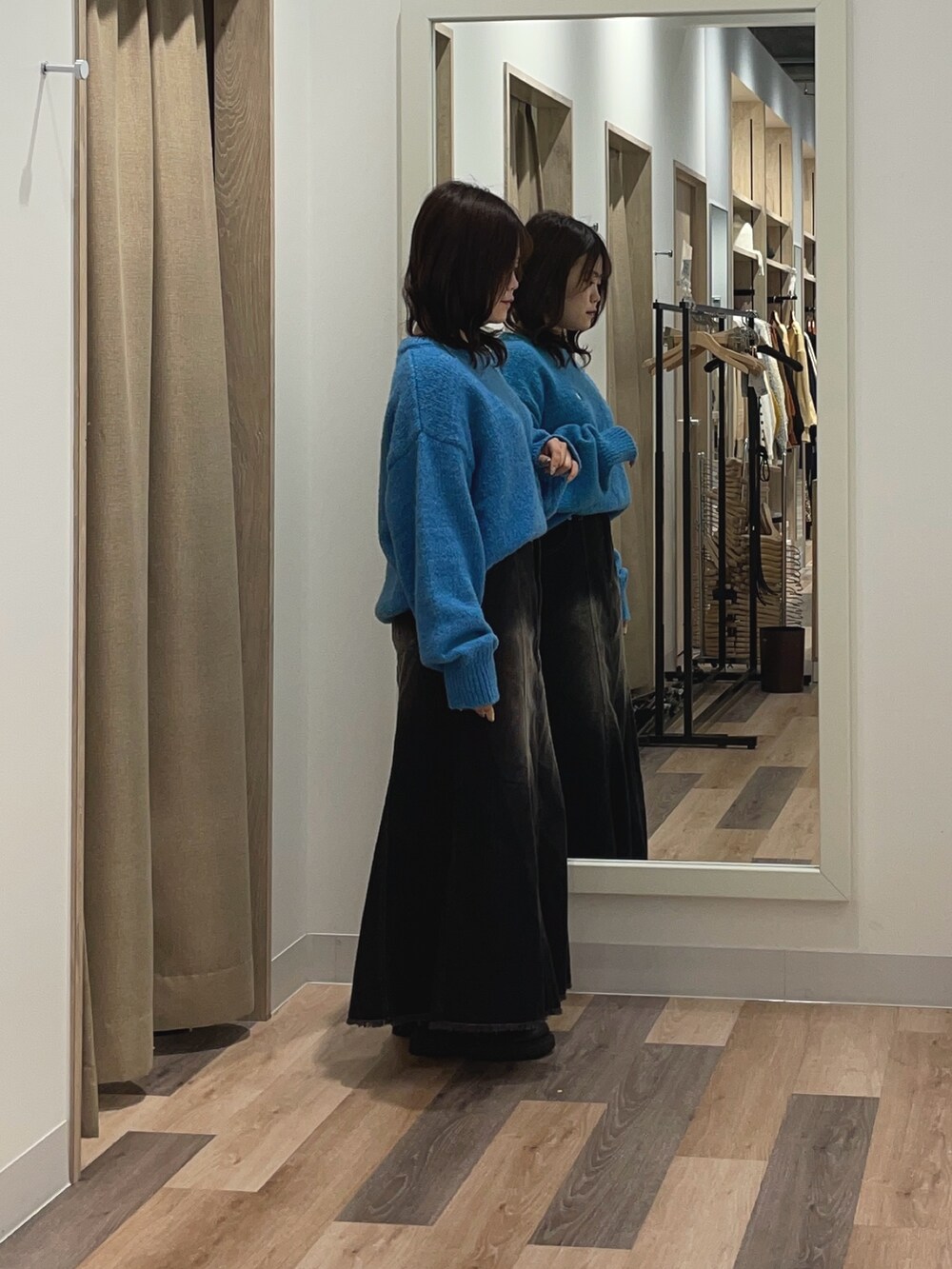ブルー系のニット/セーター、ブラック系のスカートを着用したレディースの秋コーディネートの2枚目の写真