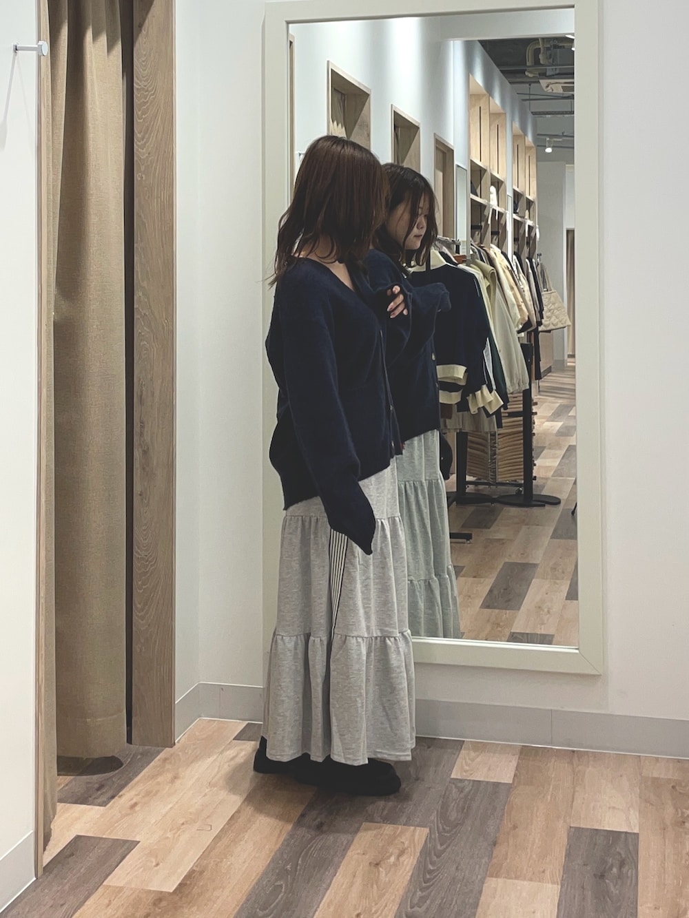 オレンジ系のカーディガン/ボレロ、ブルー系のスカートを着用したレディースの秋コーディネートの2枚目の写真